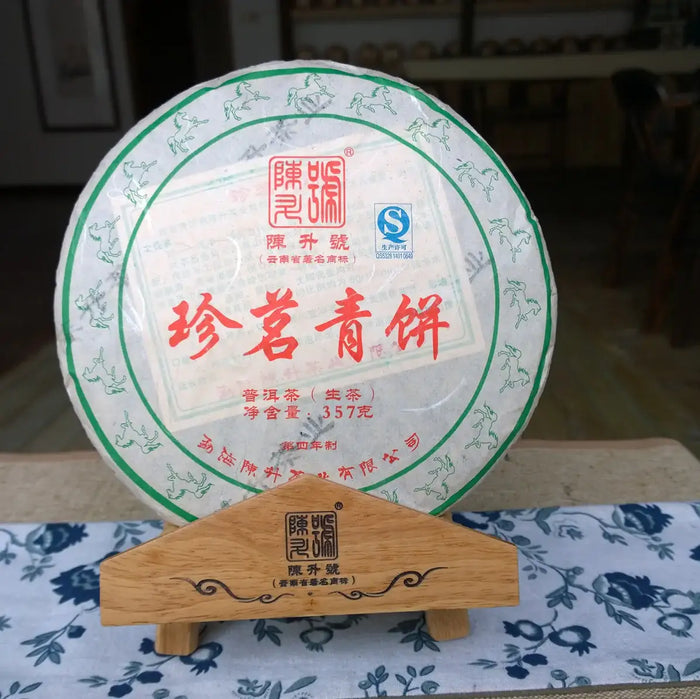 Chinese raw pu-erh tea cake, wrapped in paper with green and red Chinese characters, on a wooden stand