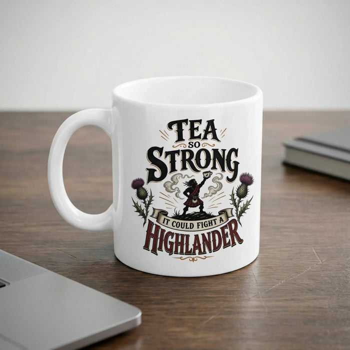 White mug with "Tea So Strong It Could Fight A Highlander" and thistle design.