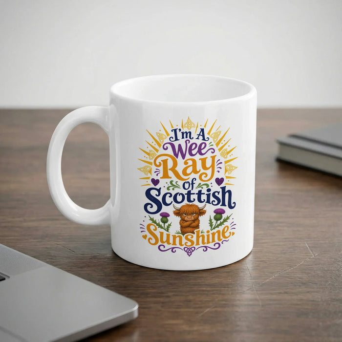White mug with "I'm a Wee Ray of Scottish Sunshine" text and Highland cow graphic.