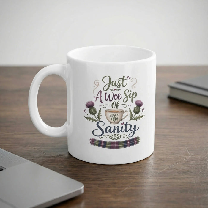 White mug with "Just A Wee Sip of Sanity" and thistle design.